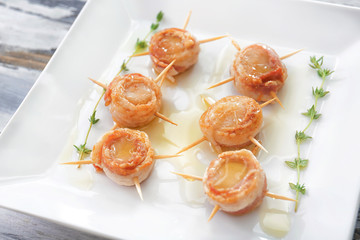 Plate with bacon wrapped scallops on table