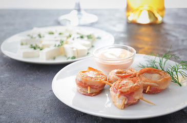 Plate with bacon wrapped scallops and sauce on table
