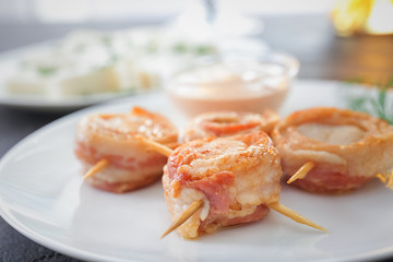 Plate with bacon wrapped scallops on table