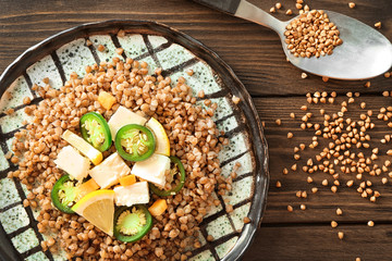 Plate with buckwheat porridge, vegetables and cheese on table
