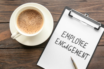 Clipboard with text EMPLOYEE ENGAGEMENT and coffee on table