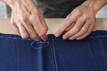 Young tailor working with textile, closeup