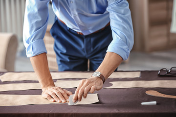 Young tailor working with sewing pattern in atelier