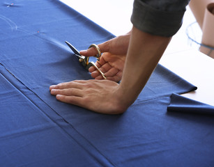 Young tailor working with textile, closeup