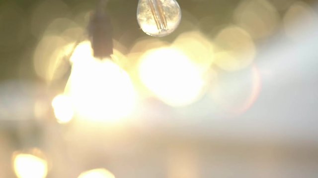 Beautiful garland hanging in slow motion outdoors near pavilion tent. String of lights glowing and moving. Holiday,decoration and festival activity concept.