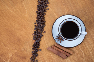 Coffee cup and beans, cinnamon sticks, on wooden table on background
