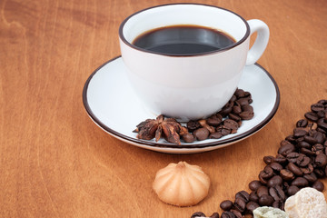 Coffee cup and beans, cinnamon sticks, on wooden table on background