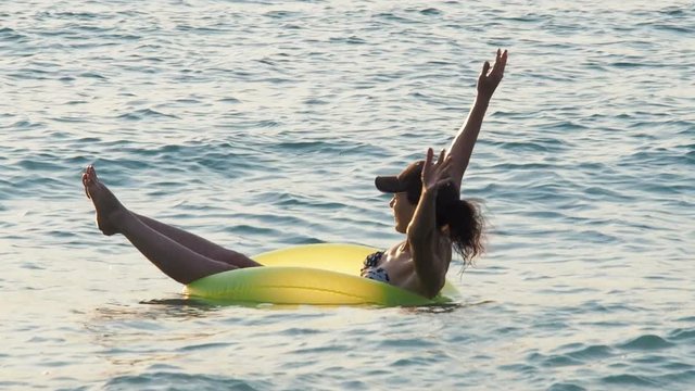 A happy girl on an inflatable circle is floating in the sea.