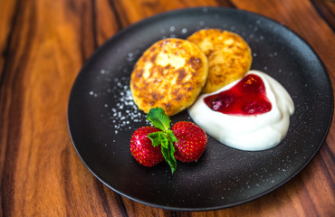 Cottage cheese pancakes. Russian syrniki with cranberry jam and yogurt, selective focus.