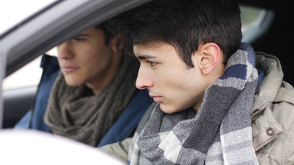 Young friends in warm clothing sitting in car and exploring dashboard while spending time together. 