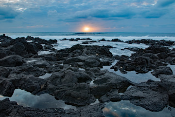 Sunrise on a cloudy day with foreground of rocks, Sandy beach, Oahu, Hawaii