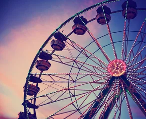 Fotobehang a fair ride shot with a long exposure at night toned with a retro vintage instagram filter app or action effect against a pink and blue cloudy sky © annette shaff