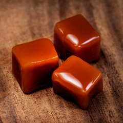 Organic caramel candies and caramel sauce on wooden background, Golden Butterscotch toffee caramels.