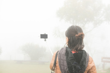 woman use smart phone to take selfie photo in mist and fog. tourist take photo in forest.