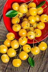 Yellow cherry in bowl on a wooden background