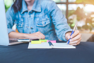 Woman hand is writing on notepad with a pen  in the office.