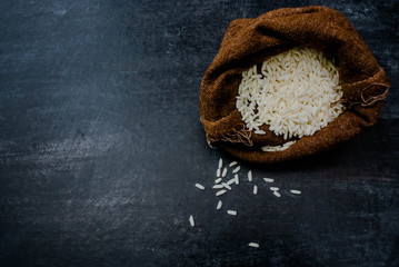 Thailand Rice on wooden table, rice in sackcloth and rice paddy on black wood,rice in sack,white rice in burlap sack with rice grain on the black wood