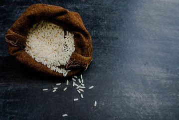 Thailand Rice on wooden table, rice in sackcloth and rice paddy on black wood,rice in sack,white rice in burlap sack with rice grain on the black wood