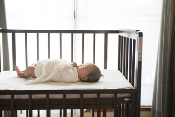 ベビーベッドに寝ている赤ちゃん - obrazy, fototapety, plakaty