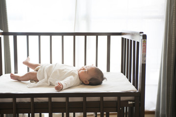 ベビーベッドに寝ている赤ちゃん - obrazy, fototapety, plakaty