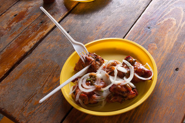 pieces of fried meat with pieces of onions on a plastic plate