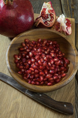 Pomegranate grains in a wooden bowl closeup
