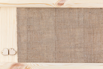 Two heart on a wooden background covered with burlap, a card for Valentine's Day.