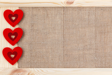 Heart on a wooden background covered with burlap, a card for Valentine's Day.
