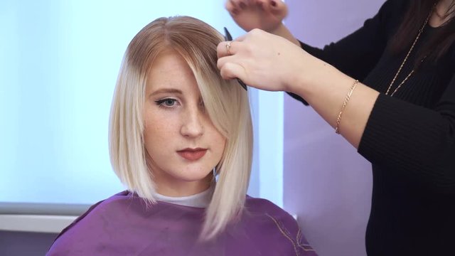 Preparing a blonde for a haircut. Woman getting new haircut by hairdresser at beauty salon. polishing hair