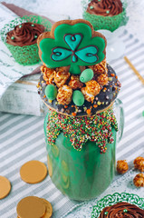 St. Patrick's Day freak shake topping with clover cookie and chocolate cupcakes on grey background
