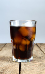 Glass with cola and ice on a wooden table