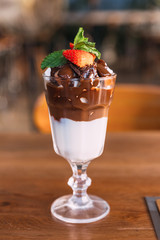 Chocolate sundae: Vanilla ice cream topping with chocolate fudge and chocolate balls with mint leaves and sliced fresh strawberry.