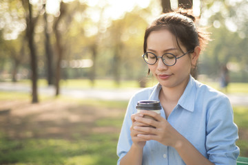 Asian woman drinking hot coffee with feeling happy in the green graden