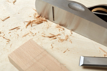 DIY concept. Woodworking and crafts. Chisel. plane and stock on the workbench. Top view. Wooden background.