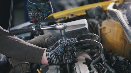 Fototapeta na wymiar Car auto service working - mechanic unscrews detail of car
