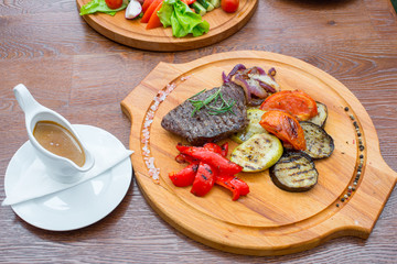 Steak with grilled vegetables, on a wooden tray