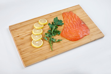 Fillet smoked trout with fresh herbs and lemon on a board. Seafood, isolated