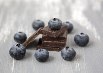 Close up Dark Chocolate Stack and Fresh Organic Blueberries on Wooden Background Natural Light Selective Focus