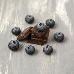 Close up Dark Chocolate Stack and Fresh Organic Blueberries on Wooden Background Natural Light Selective Focus