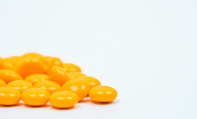 Yellow sugar coated tablets pills on white background with copy space. Medicine for treatment constipation.