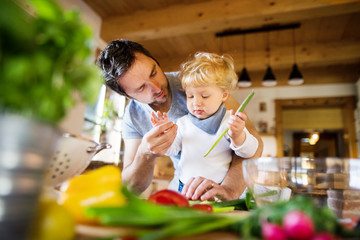 Young father with a toddler boy cooking.