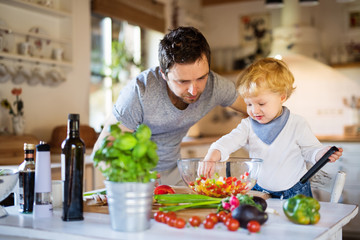 Young father with a toddler boy cooking.