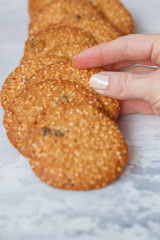 woman's hand takes a round healthy biscuit made of white sesame and raisins