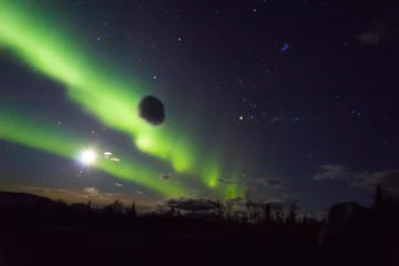 Cercles muraux Denali northern lights arcoss the blacked skies of an Alaskan life staring up at the stars.  Northern lights across the black spruces on the Alaskan Range, Silhouettes cast across the sky and clouds cascaded