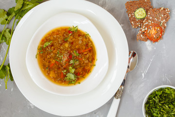 Peruvian quinoa soup, red rice and lentils in a white plate with herbs and crispbread.