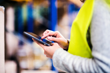 Woman warehouse worker with tablet.