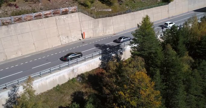 Car on a mountain road, Cinema 4k aerial pan view following cars driving towards a huge bridge, between apine, on a sunny fall day, on simplon pass, in wallis, of the alps in Switzerland