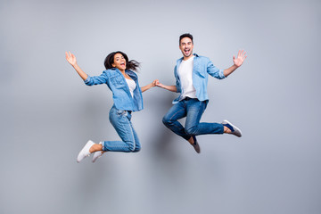 Fototapeta na wymiar He vs She full length portrait of attractive, playful, cheerful, hispanic couple in casual outfit jumping with opened mouths over grey background