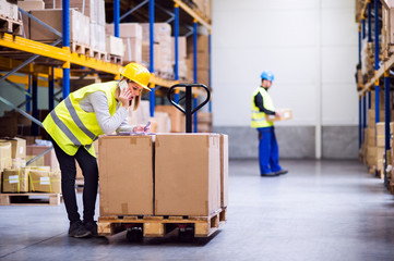 Young warehouse workers with smartphone.