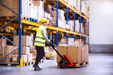 Woman warehouse worker with hand forklift truck.